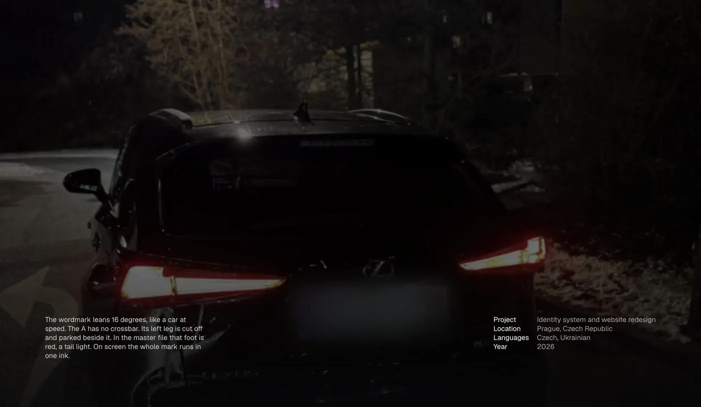The wordmark over a delivered car at night; the red foot of the A lands as the tail lights come up